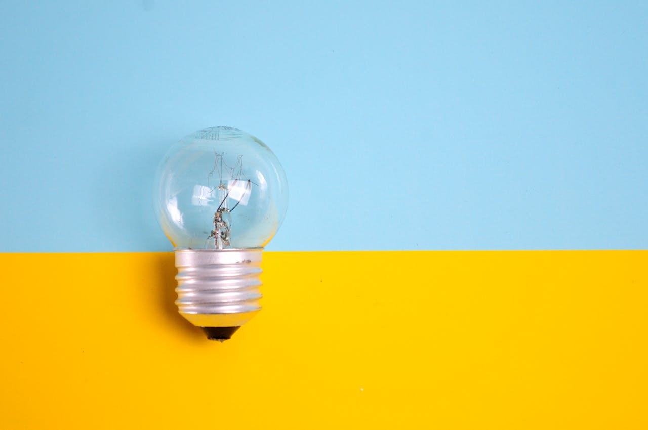 our-story A clear light bulb against a vibrant blue and yellow background, symbolizing energy and creativity.